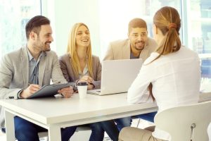 Two men and two women talking with a laptop in front of them