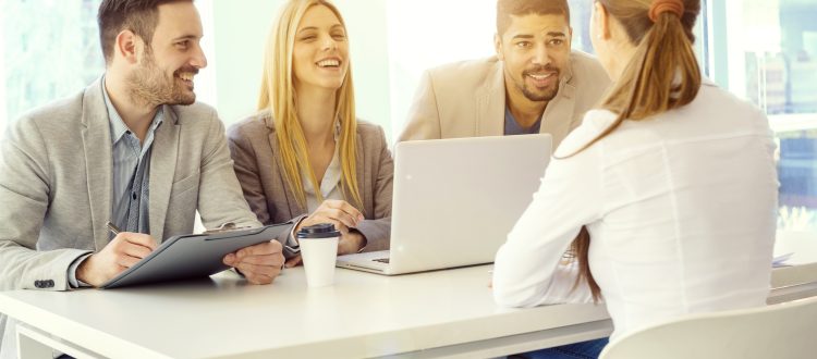 Two men and two women talking with a laptop in front of them